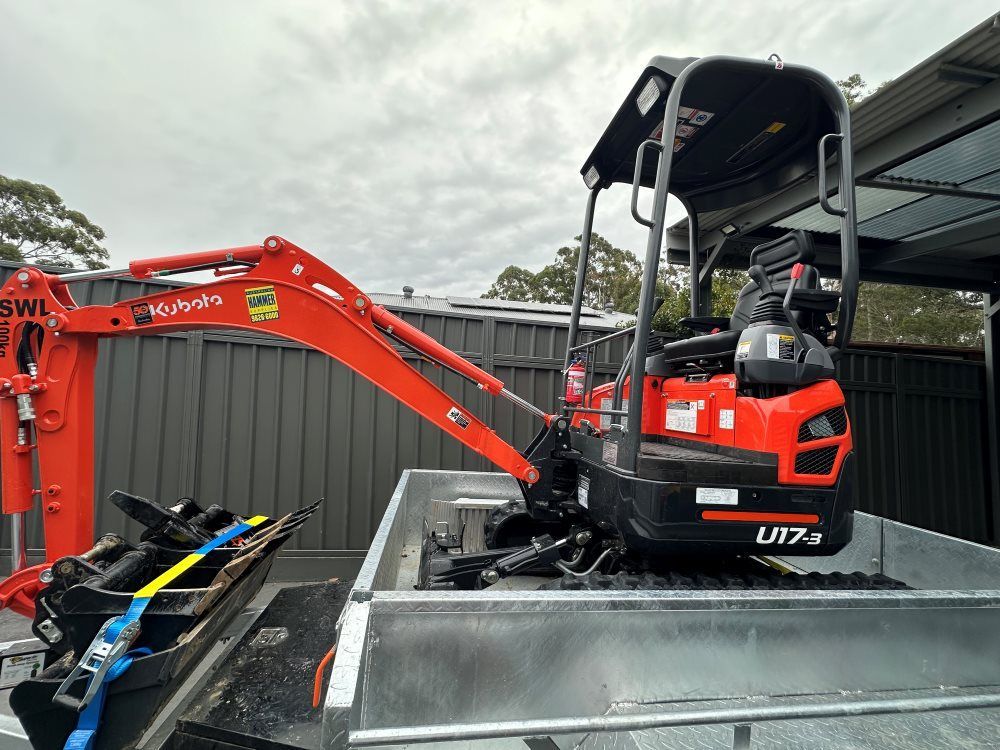 A Small Red Excavator is Sitting on Top of a Trailer — Garrett's Excavation & Equipment Hire in Sanctuary Point, NSW