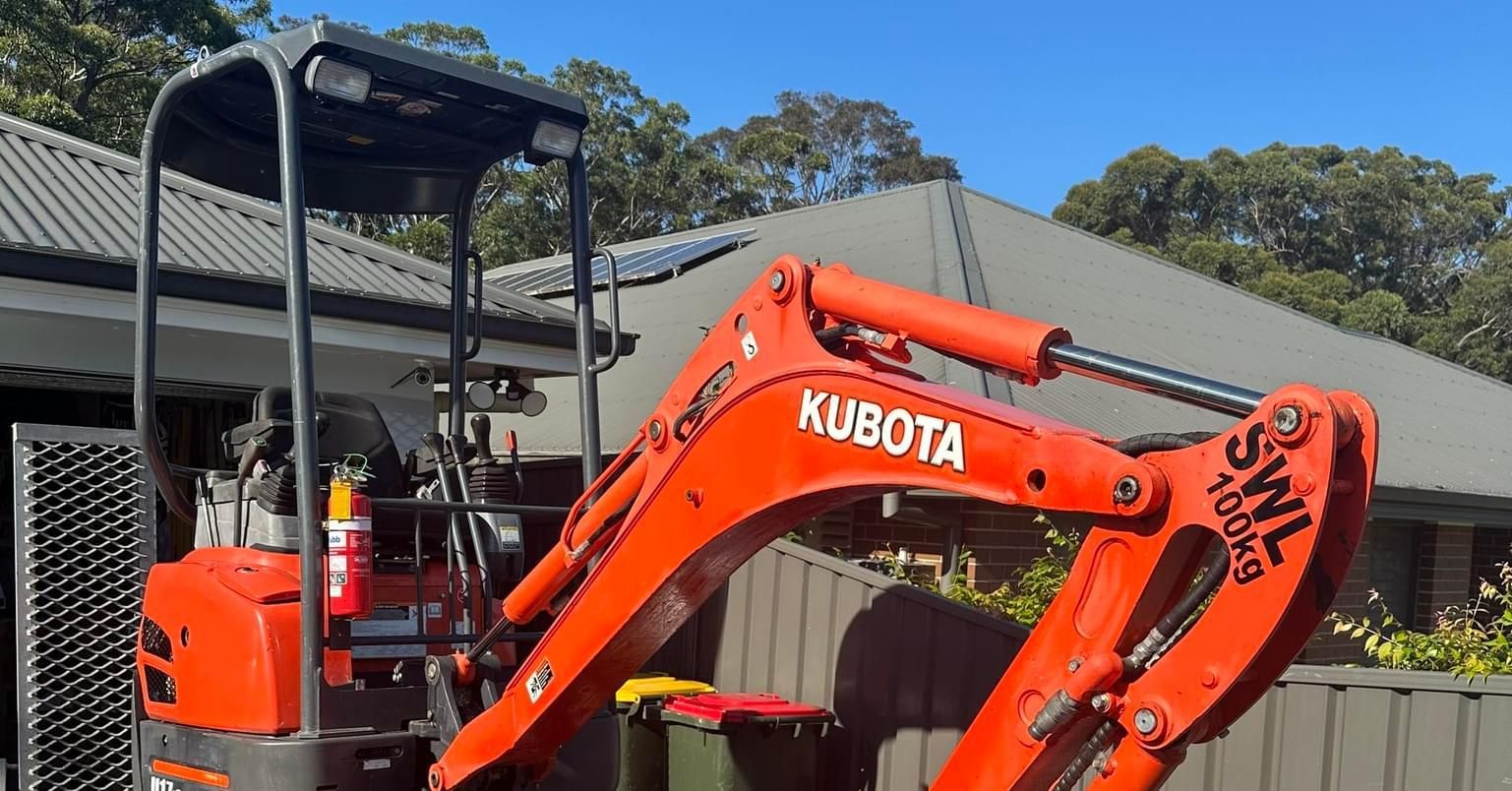 A Red Kubota Excavator is Parked in Front of a House — Garrett's Excavation & Equipment Hire in Huskisson, NSW