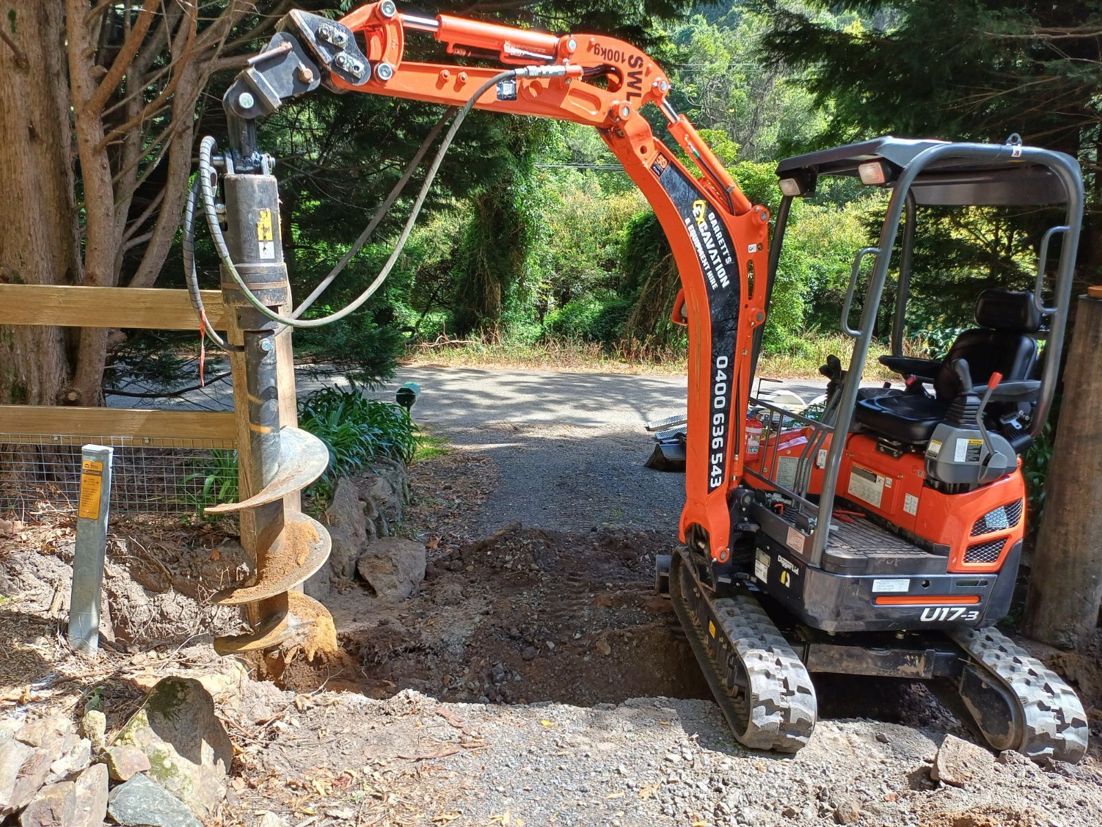 A Small Orange and Black Excavator is Digging a Hole in the Ground — Garrett's Excavation & Equipment Hire in Sanctuary Point, NSW