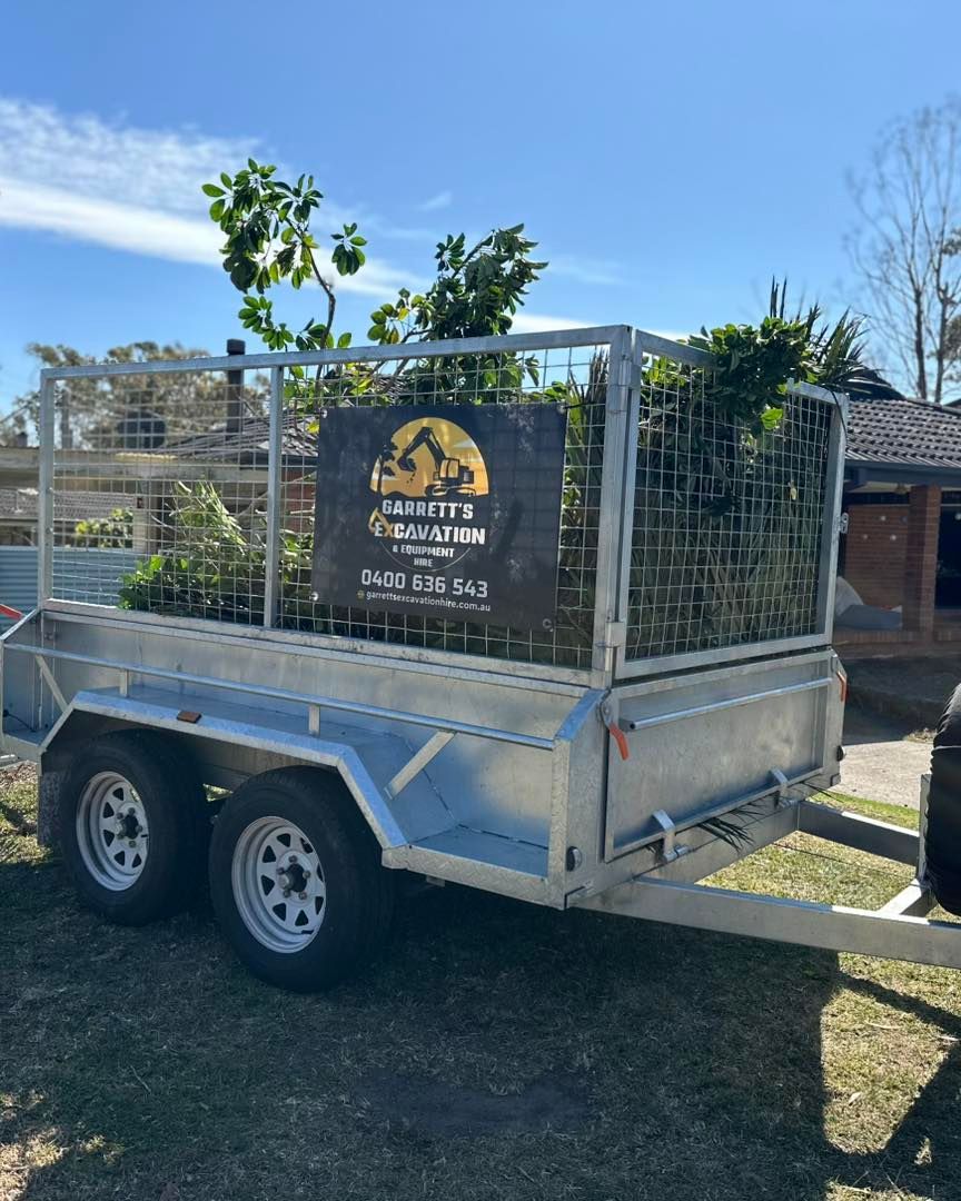 A Trailer With a Sign on It is Parked in the Grass — Garrett's Excavation & Equipment Hire in Nowra, NSW