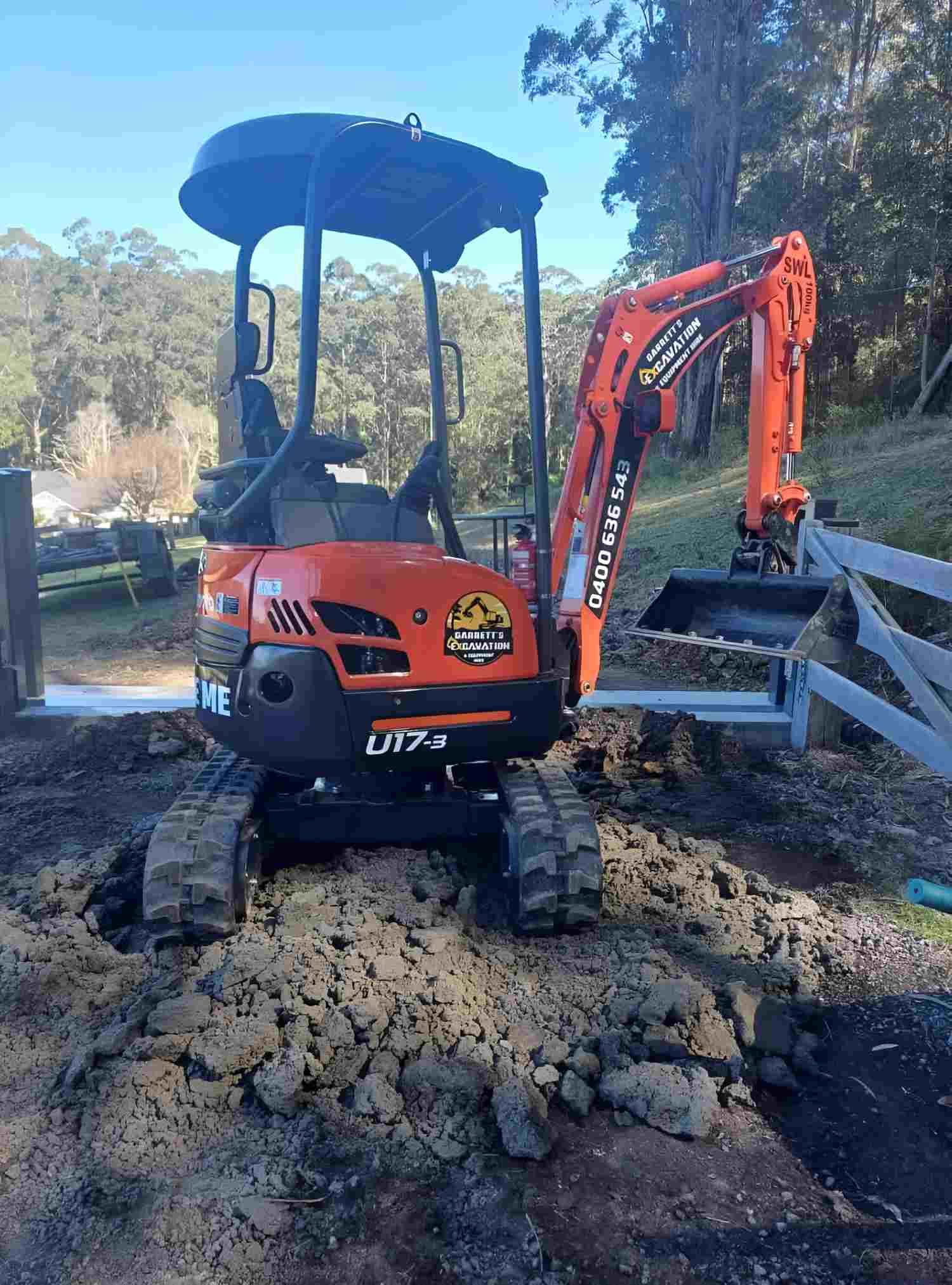 A Small Orange Excavator is Sitting on Top of a Pile of Dirt — Garrett's Excavation & Equipment Hire in Sanctuary Point, NSW