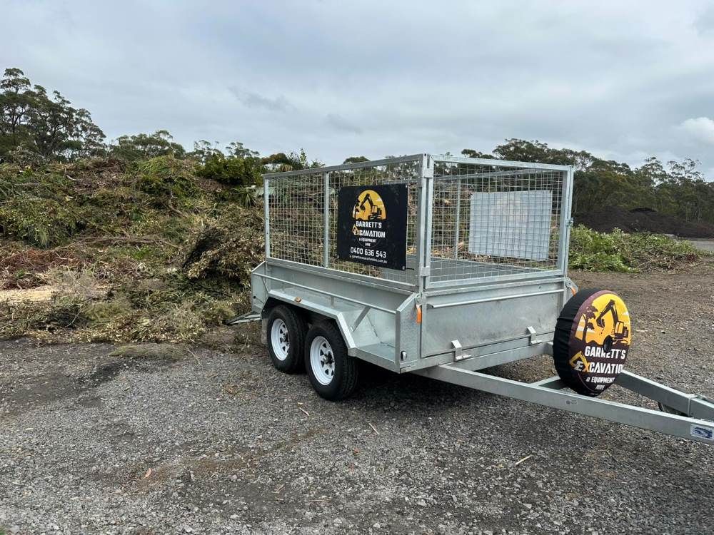 A Trailer is Parked in Front of a Pile of Brush — Garrett's Excavation & Equipment Hire in Vincentia, NSW