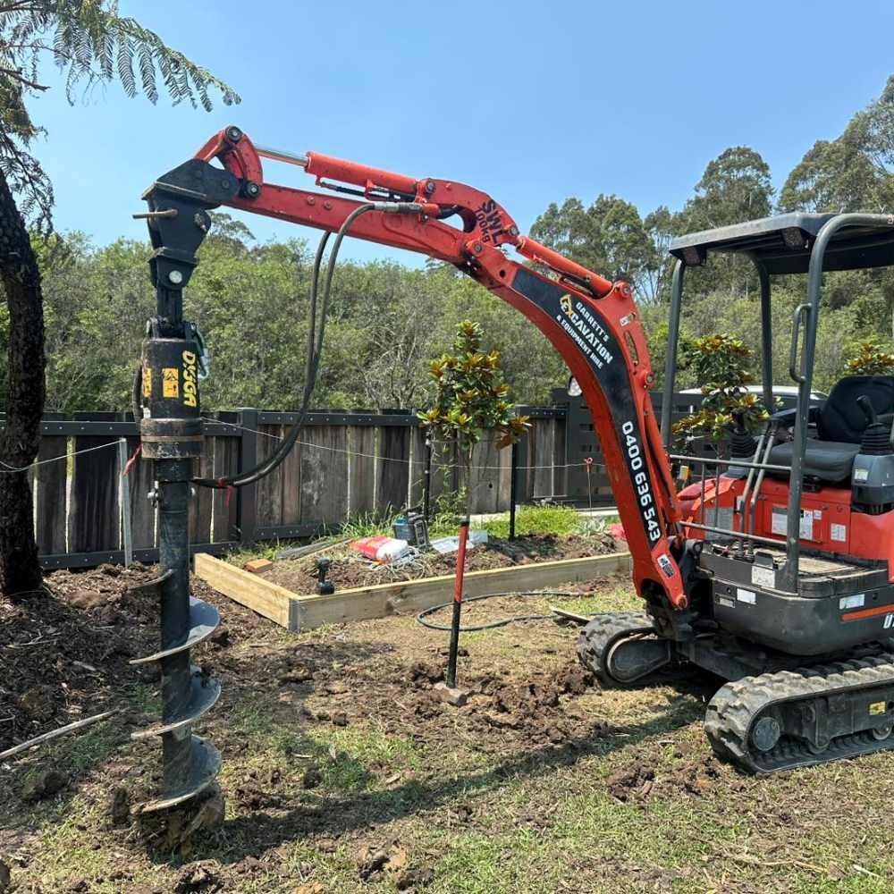 A Small Excavator is Digging a Hole in the Ground — Garrett's Excavation & Equipment Hire in Wandandian, NSW