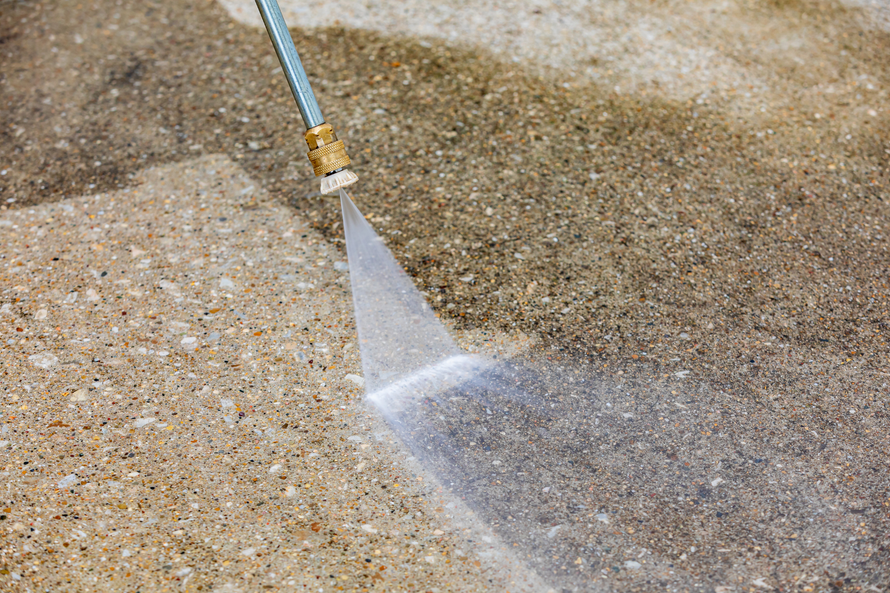 Water spraying from a hose over gravel and sand on the ground