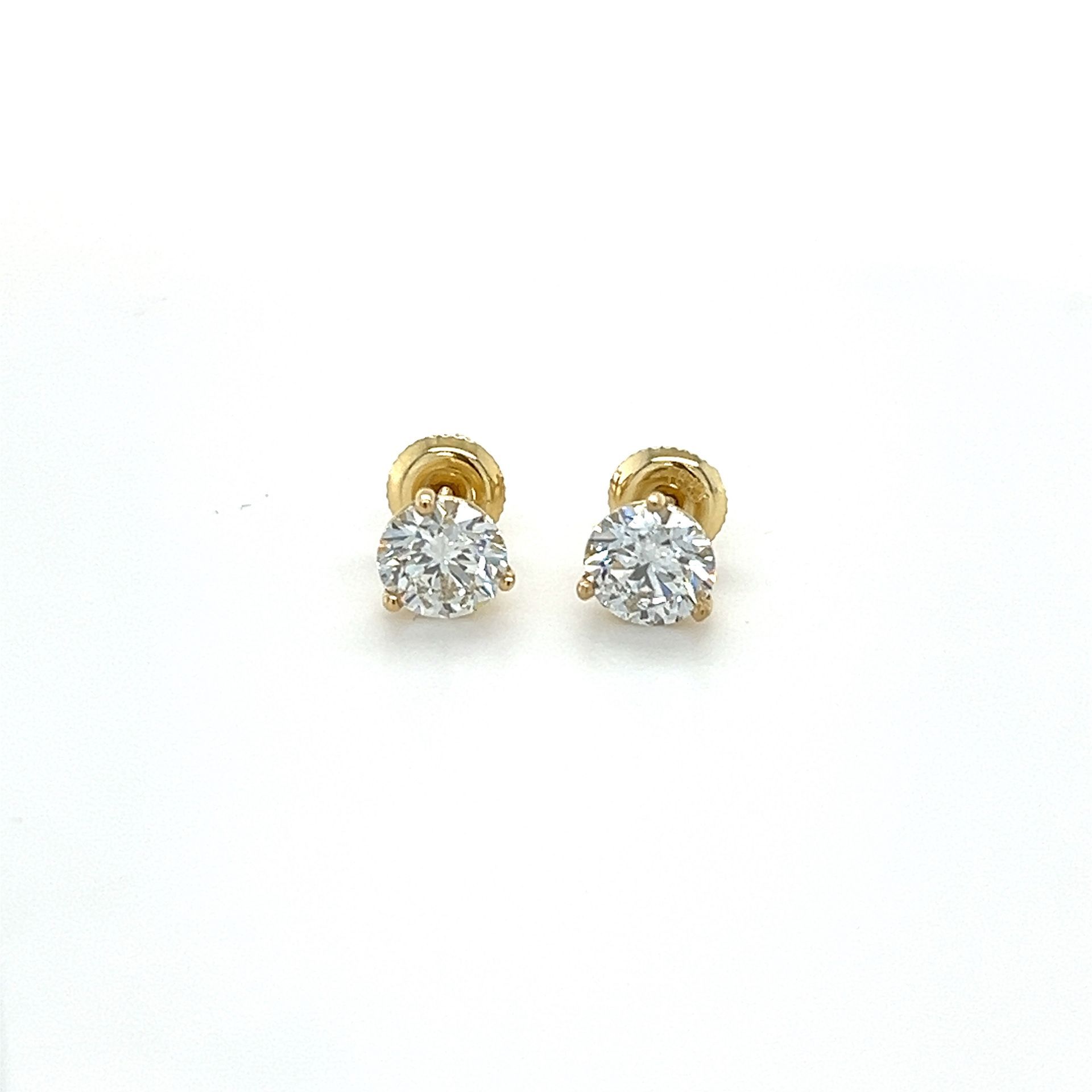 A pair of diamond stud earrings in yellow gold on a white background.