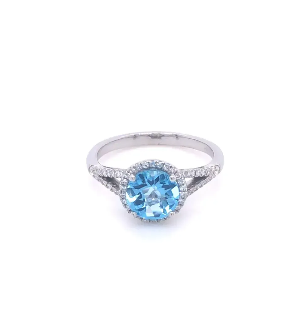 A white gold ring with a blue topaz and diamonds on a white background.