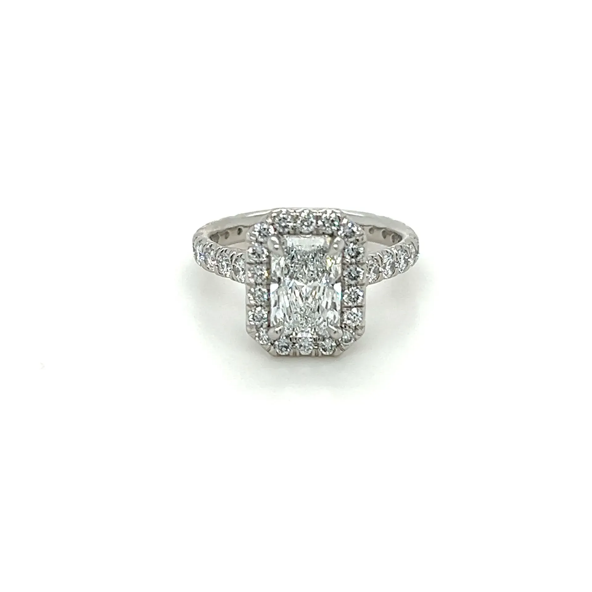 A white gold ring with an emerald cut diamond in the center surrounded by smaller diamonds.