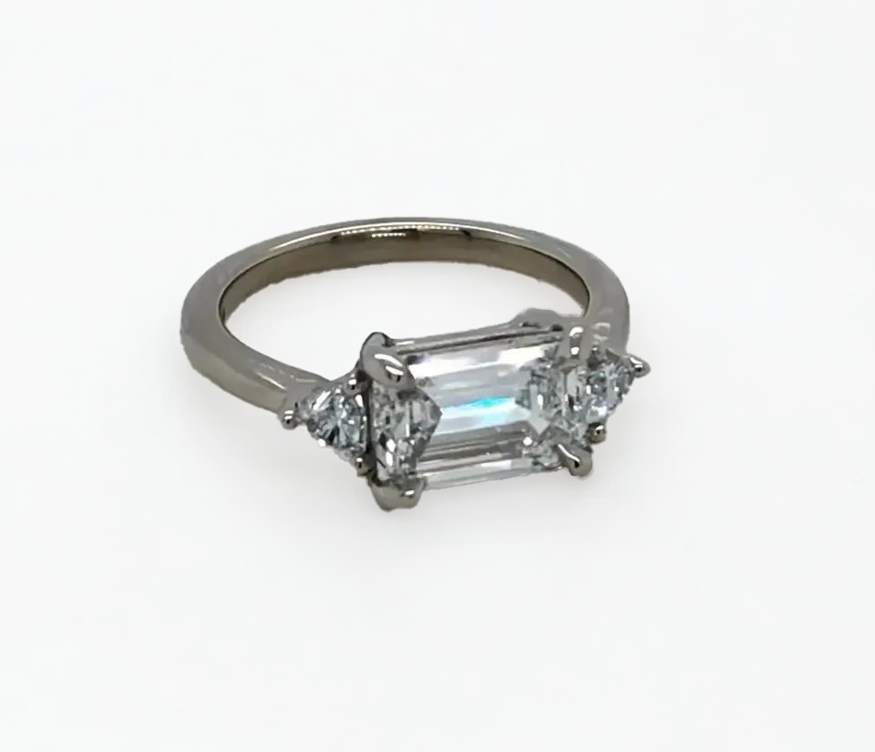 A white gold ring with an emerald cut diamond in the center