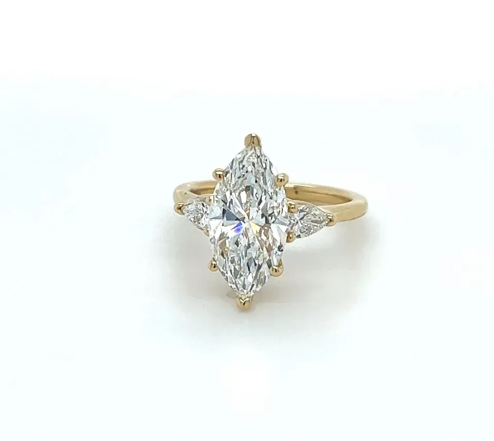 A yellow gold ring with a marquise cut diamond on a white surface.
