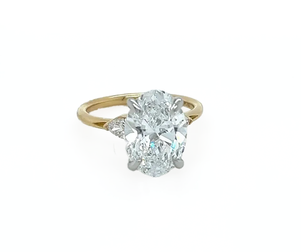 A yellow gold ring with an oval diamond on a white surface.
