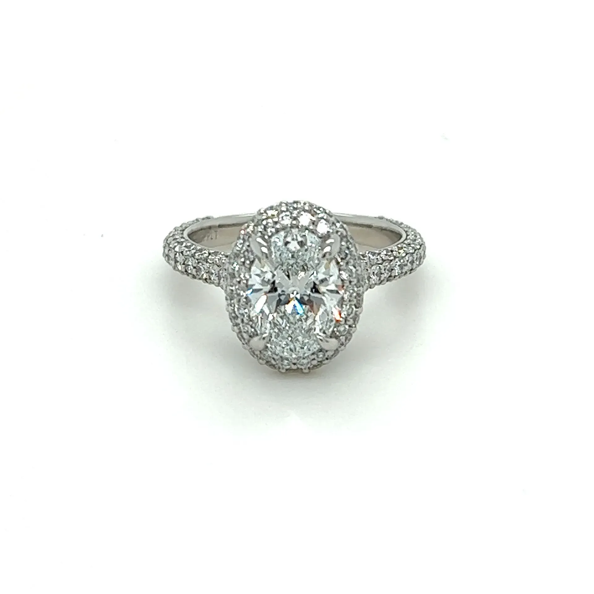 A white gold ring with an oval diamond in the center surrounded by smaller diamonds.