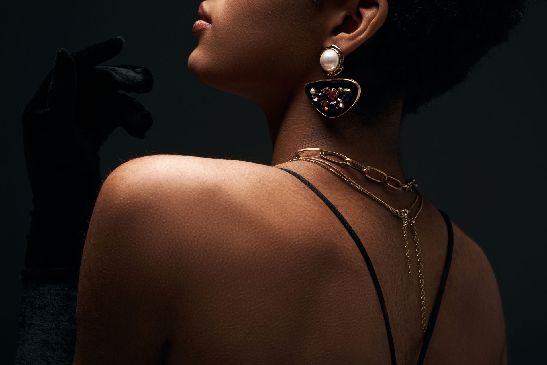 The back of a woman wearing a necklace and earrings.