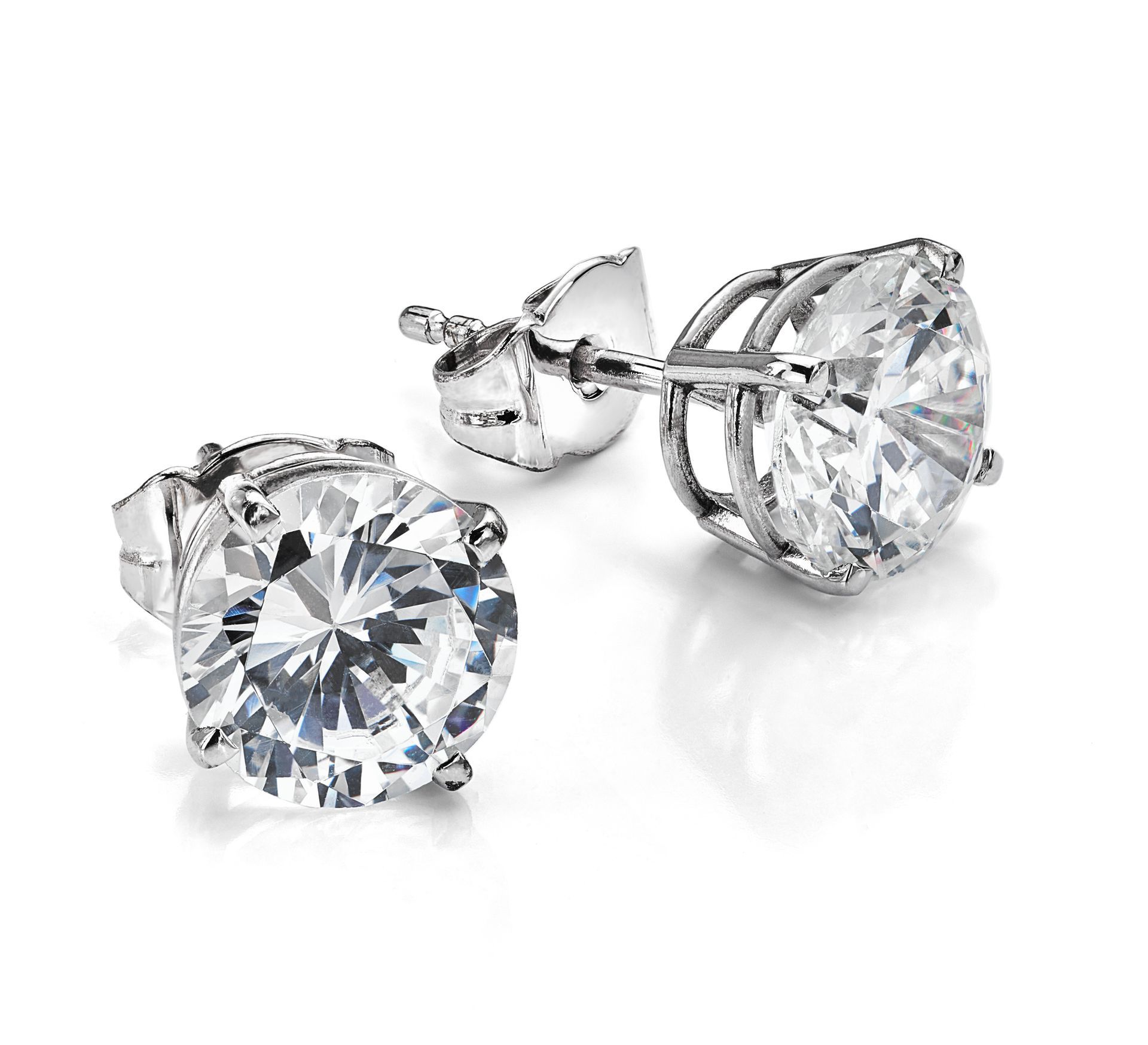 A pair of diamond stud earrings on a white surface.