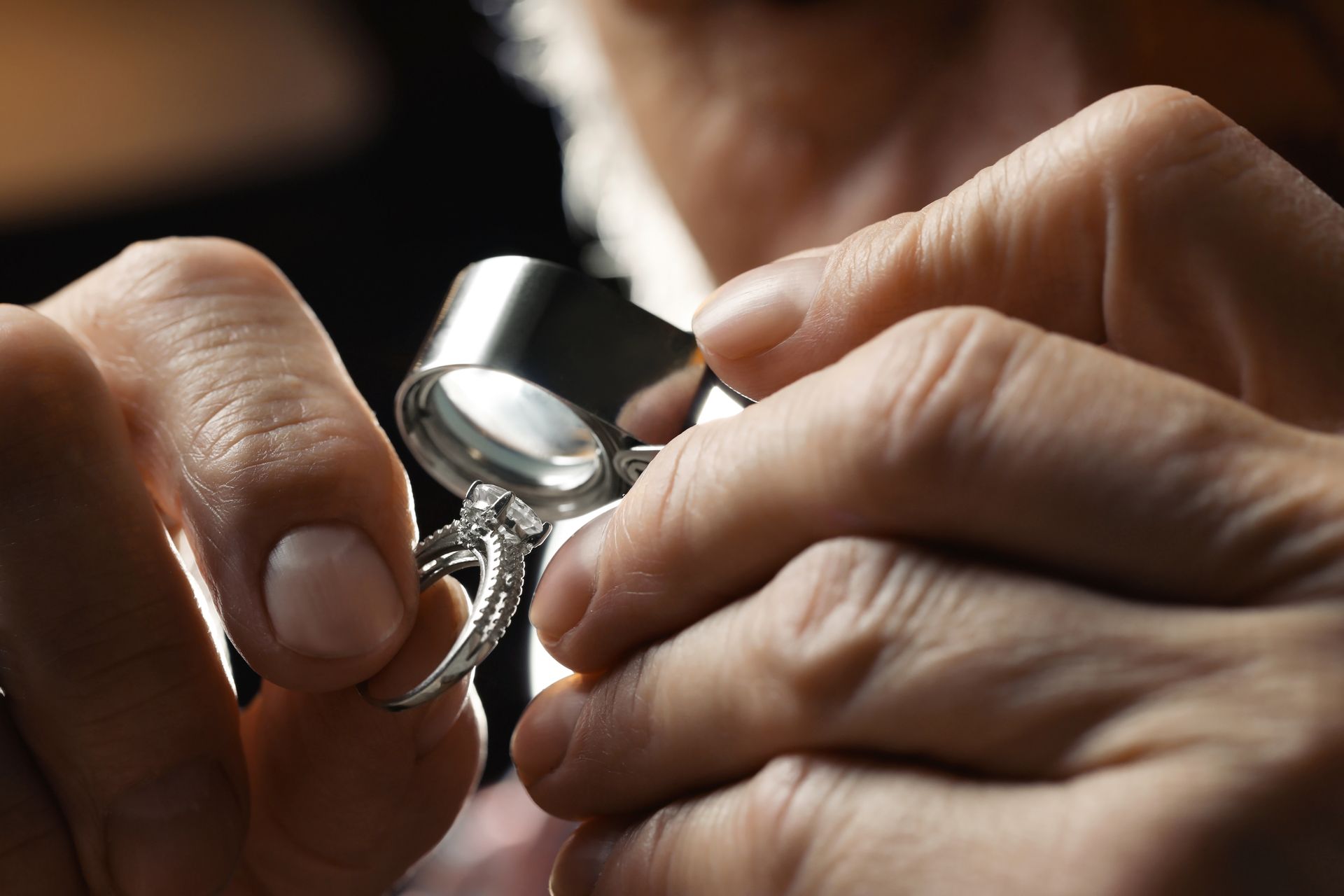A person is looking at a ring through a magnifying glass.