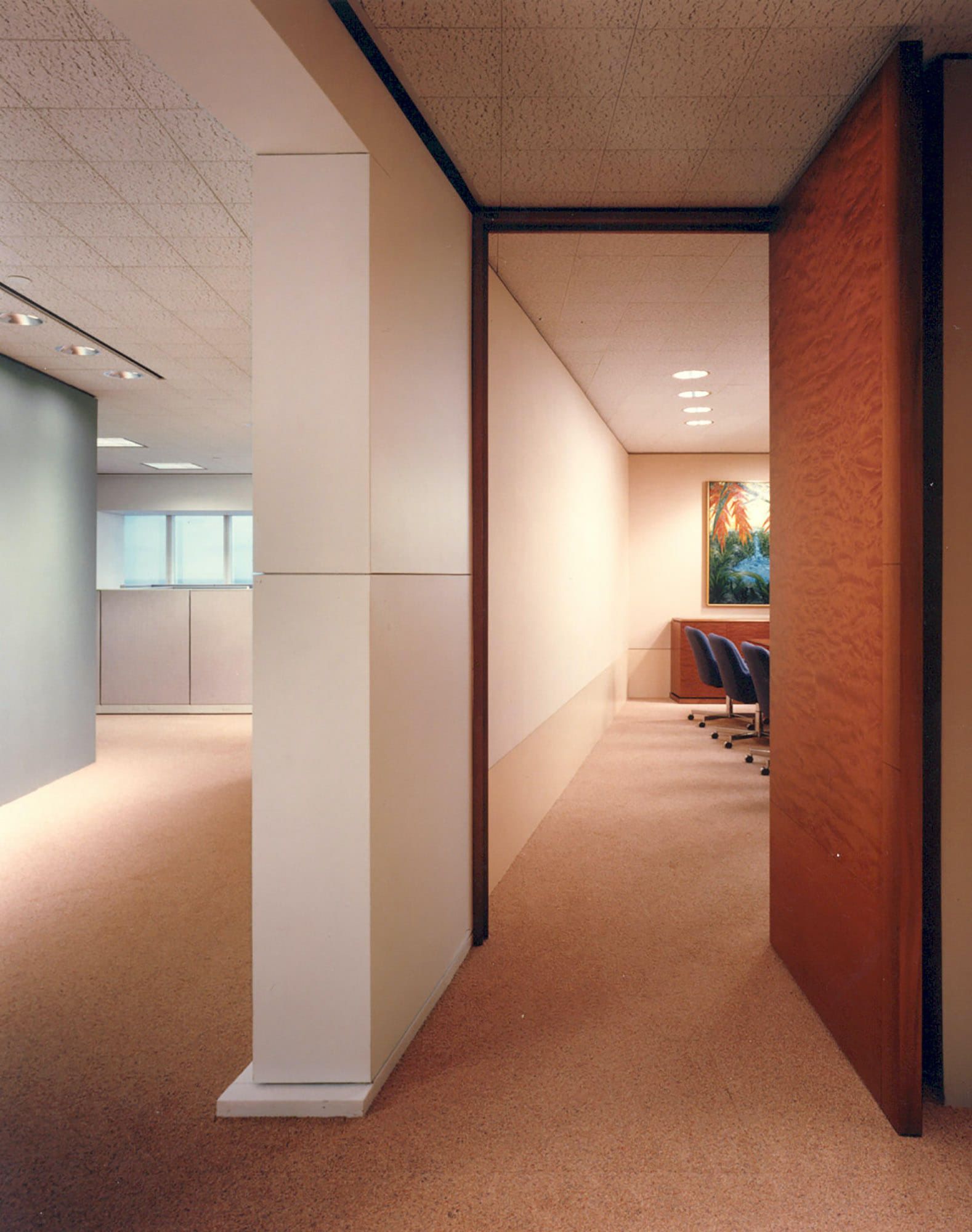 a hallway leading to a meeting room with a painting on the wall