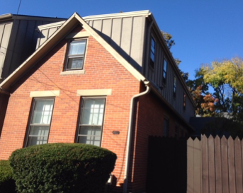 a brick house with a metal roof and a wooden fence