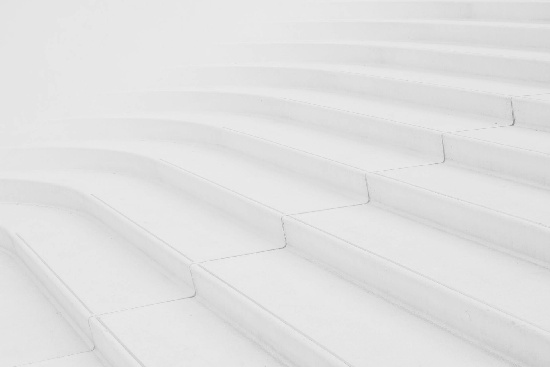 a row of white stairs leading up to a white wall .