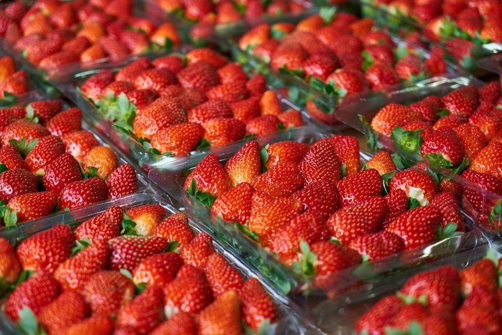 A bunch of strawberries in plastic containers on a table.