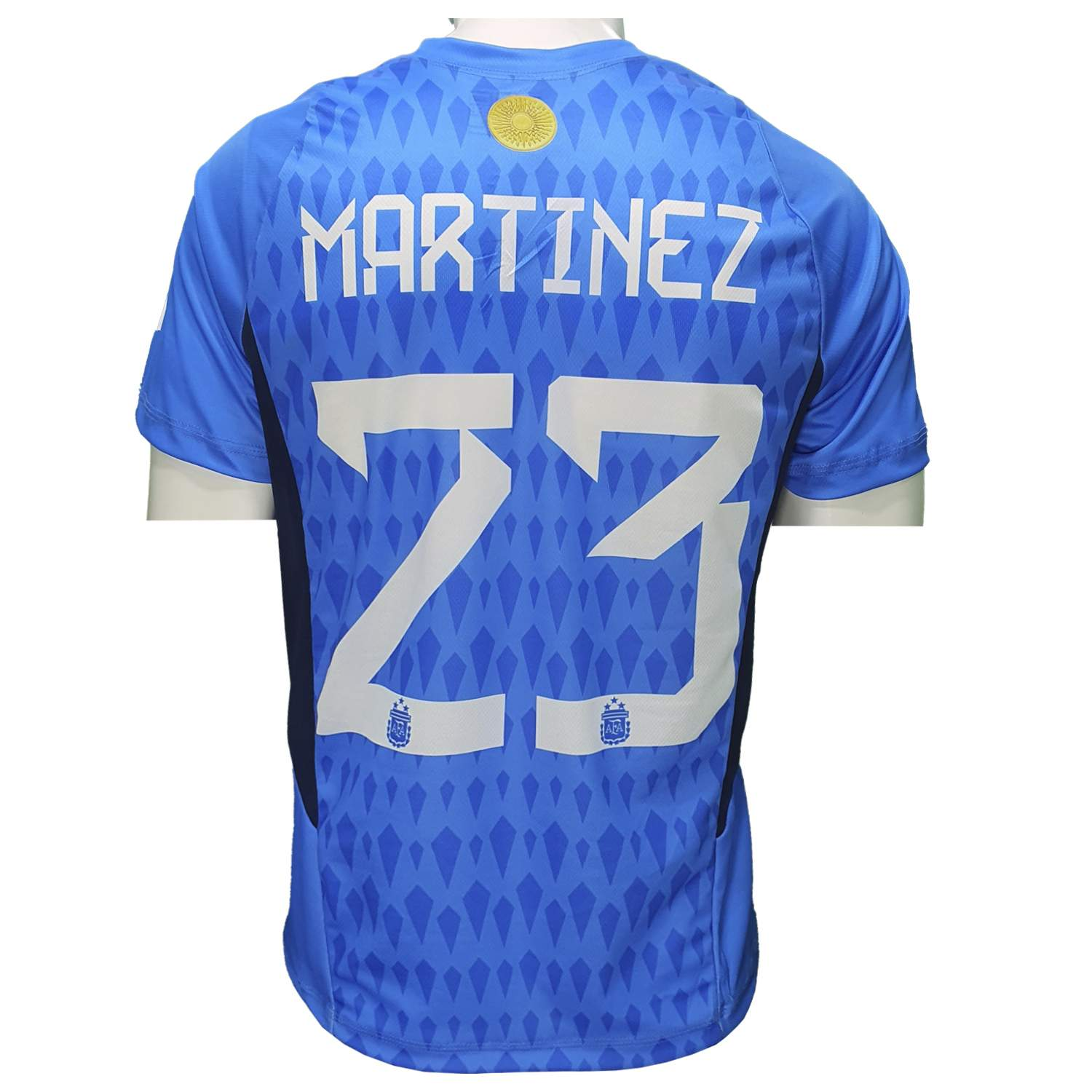 Camiseta de fútbol azul con "Martínez" y el número "23" en la espalda. Presenta un sutil estampado de rombos.