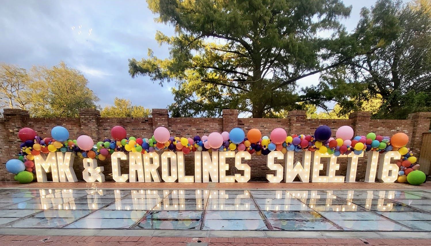 A sign that says `` mk & carolines sweet 16 '' is surrounded by balloons.