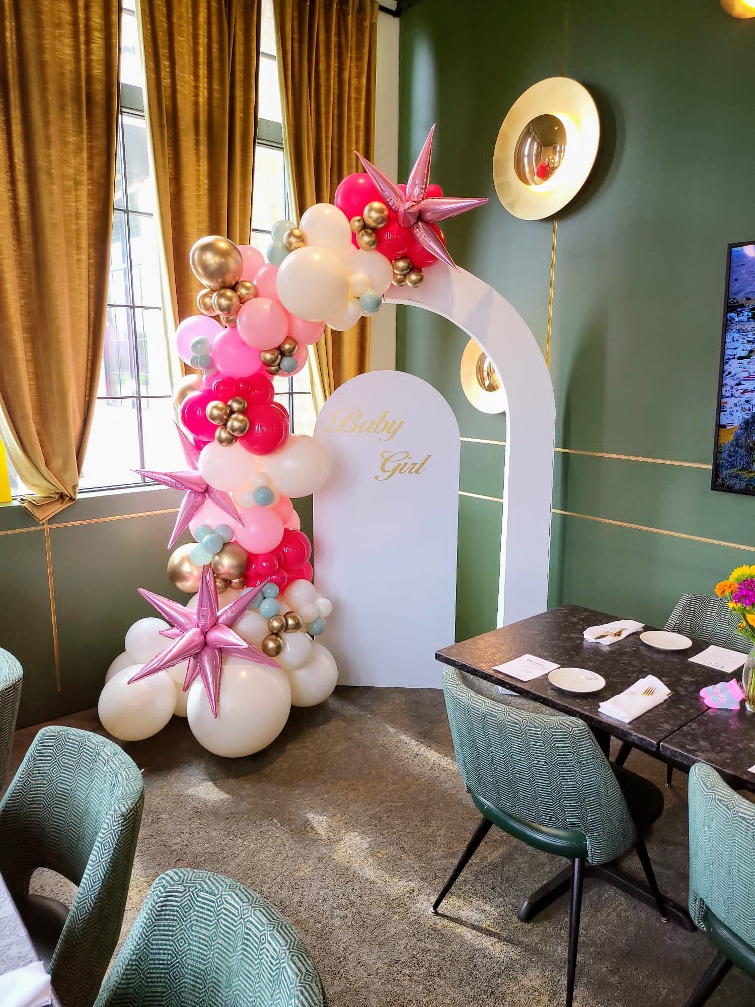 A room with tables and chairs and a balloon arch.