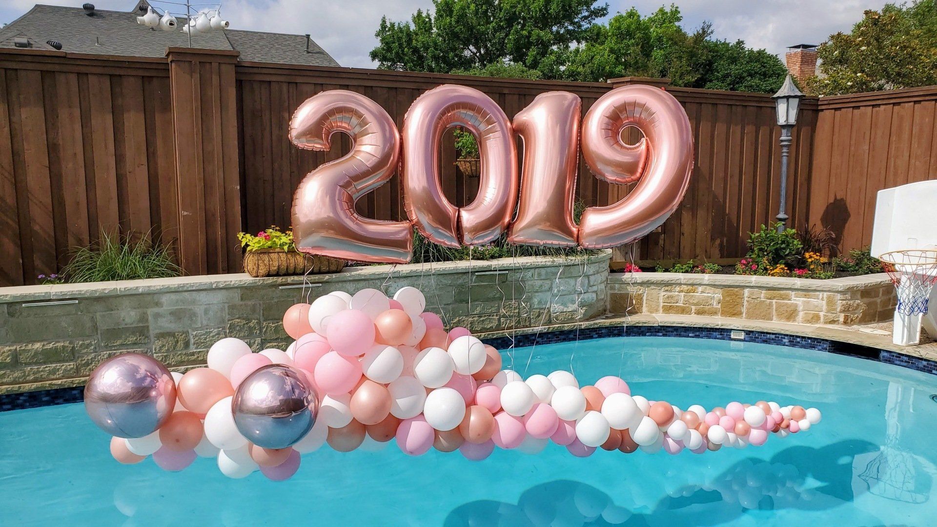 A pool decorated with balloons and a sign that says `` 2019 ''.