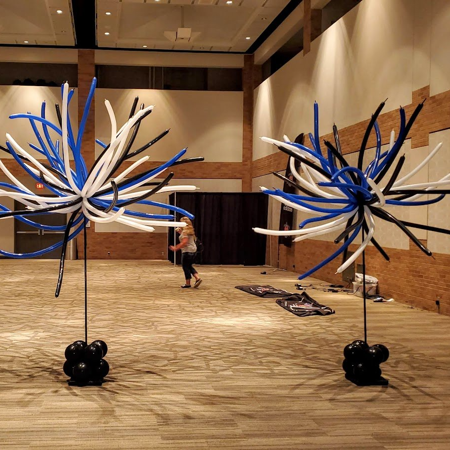 A woman is standing in a room surrounded by blue and white balloons