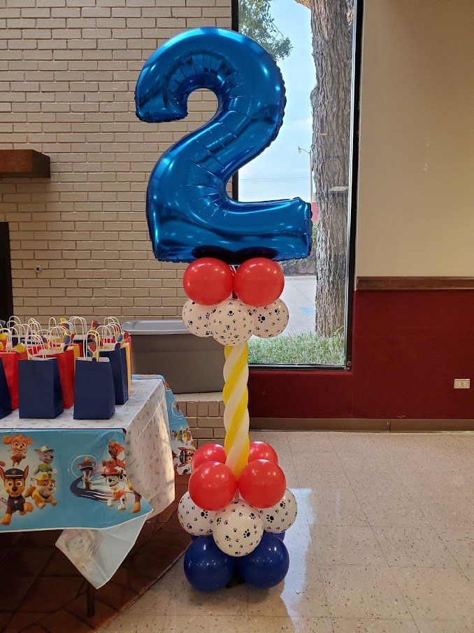 A blue number 2 balloon is sitting on top of a stack of red and white balloons.