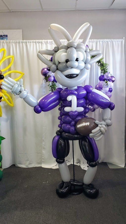 A mascot made out of balloons is holding a football.