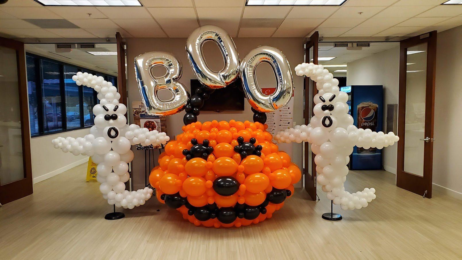 A room decorated with balloons for halloween including a pumpkin and ghosts.