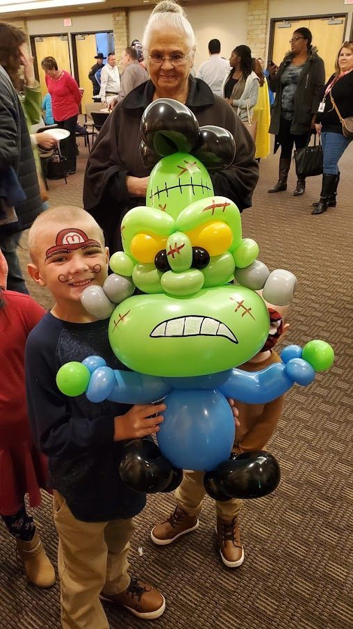 A woman and a boy are holding a monster made out of balloons.