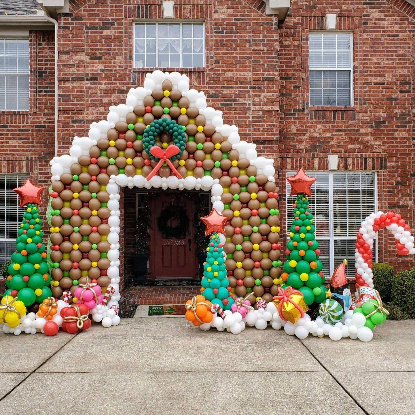 A gingerbread house made out of balloons and christmas trees
