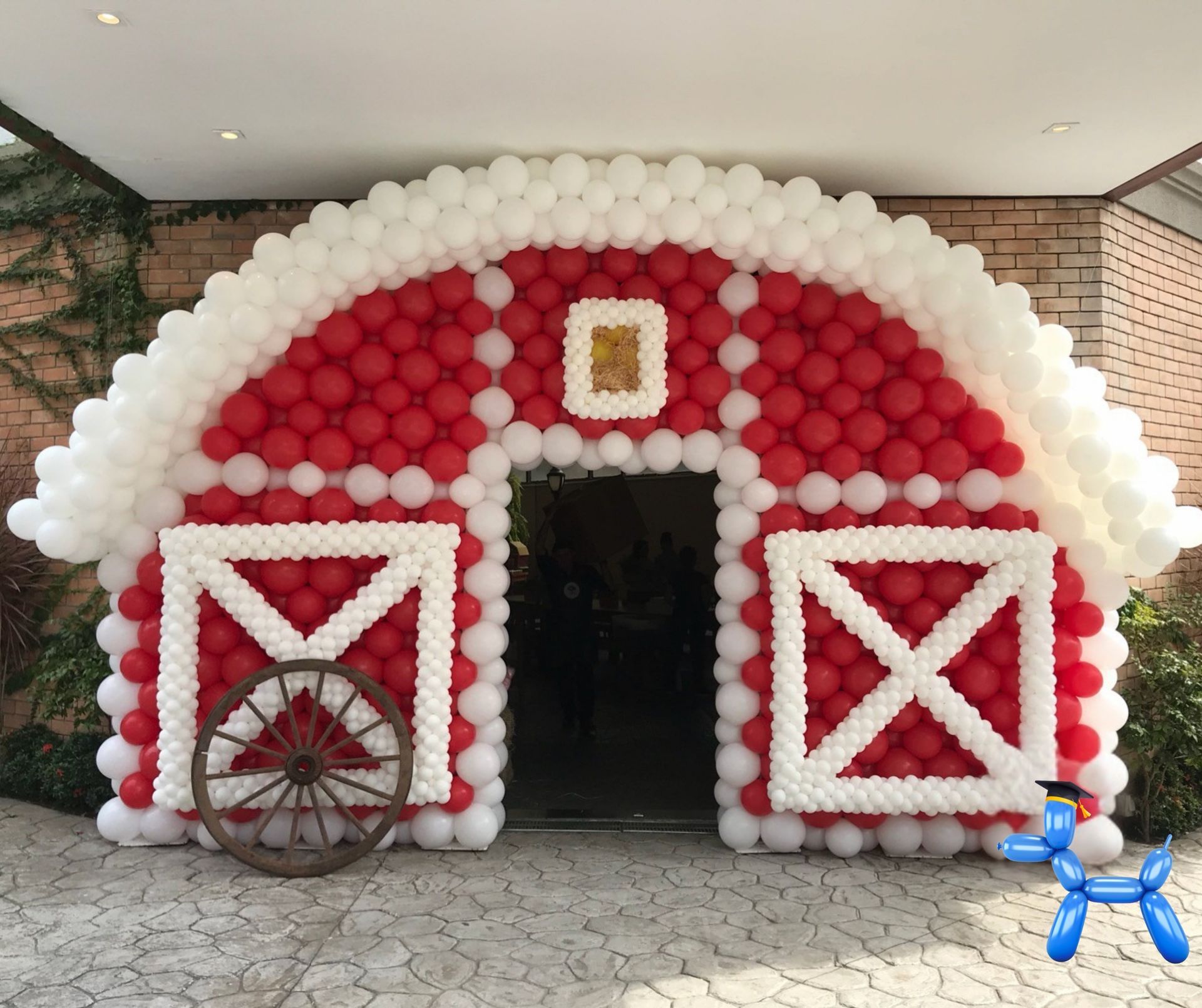 Barn house balloon sculpture in red and white balloons framing the entrance for the venue with western accents