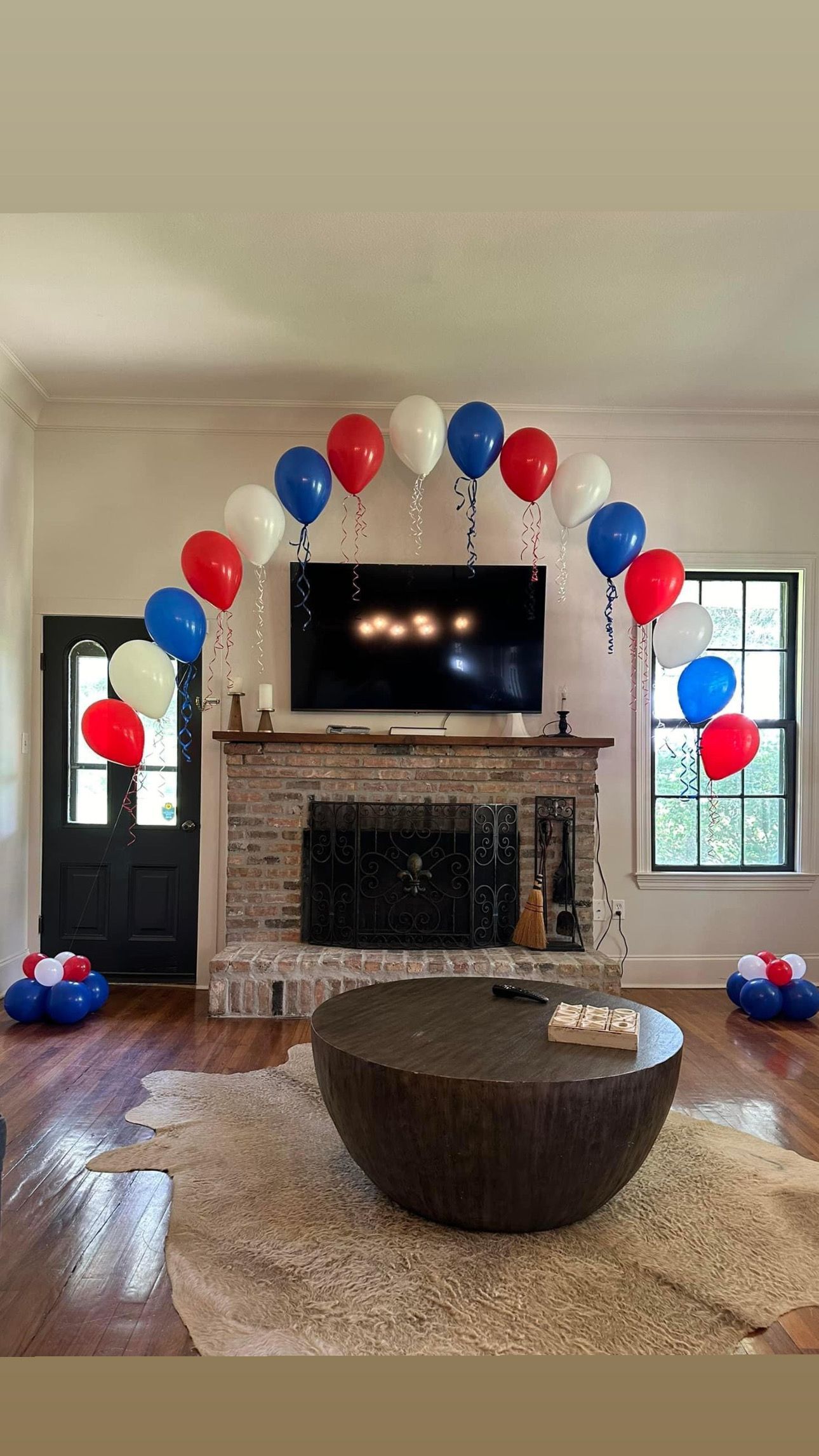 A living room decorated with red , white and blue balloons.