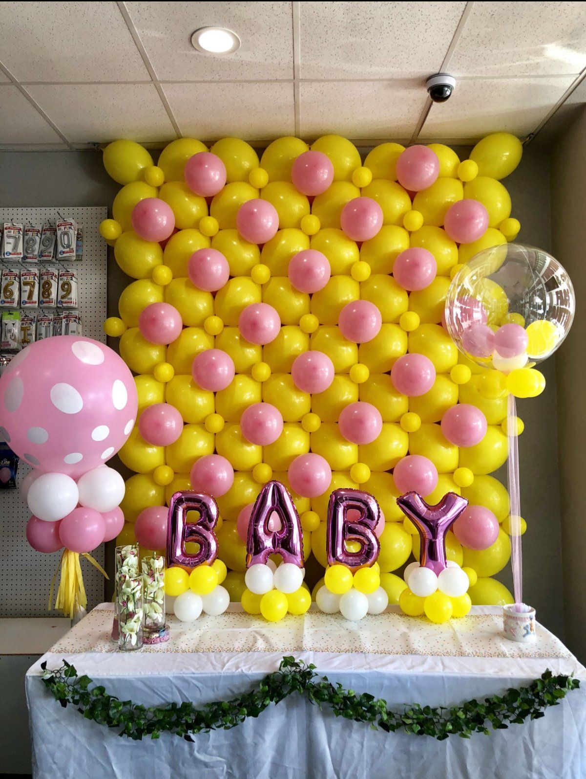A wall of pink and yellow balloons with the word baby on it