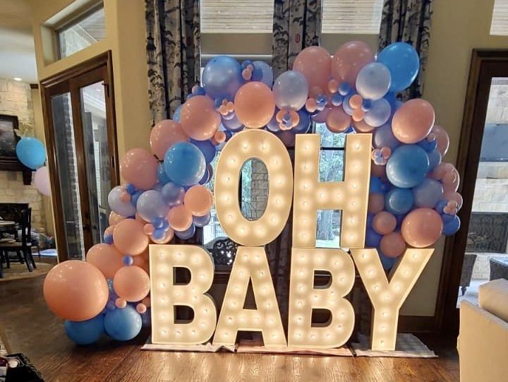 A sign that says oh baby is surrounded by balloons.