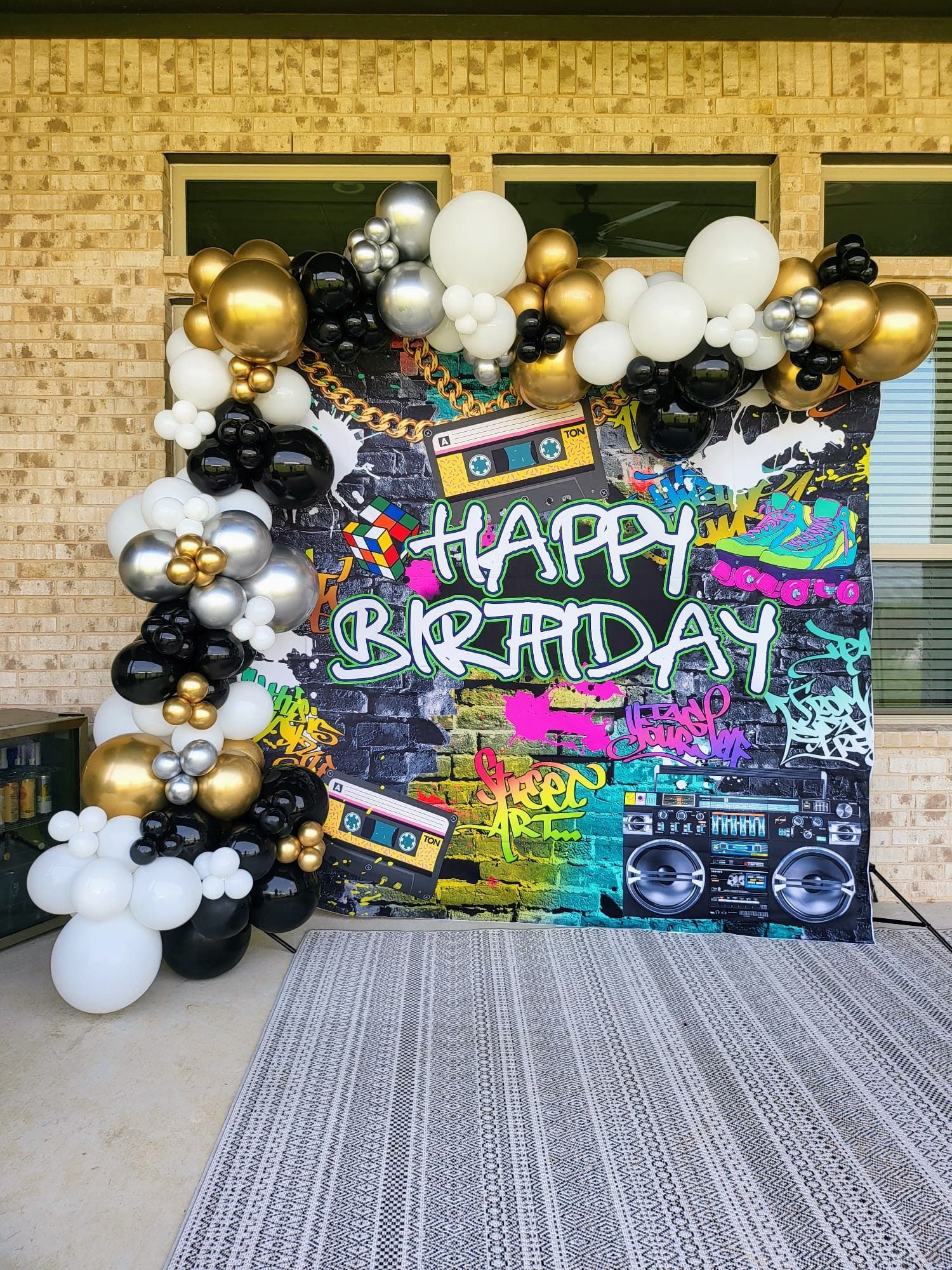 A birthday backdrop with balloons and graffiti on it.