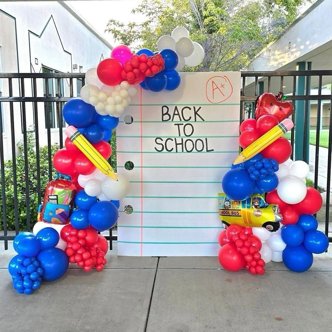 A back to school backdrop with red, blue, and white balloon garland.
