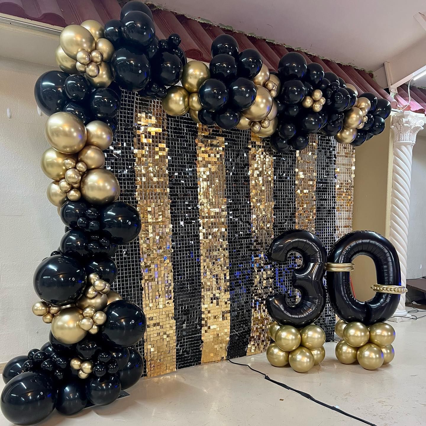 Black and gold shimmer wall backdrop with balloon garland for luxury event in Fort Worth