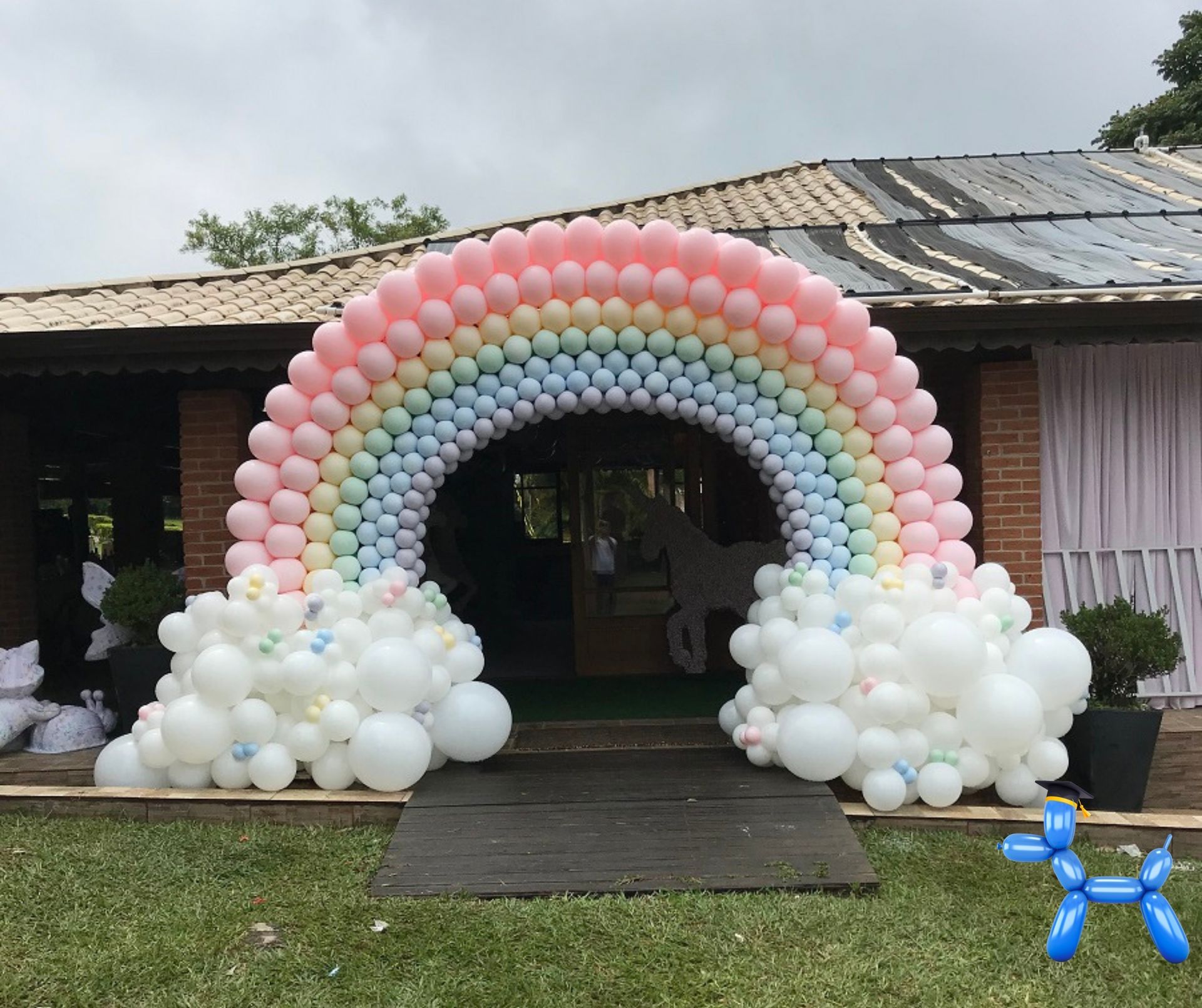Pastel colored rainbow balloon arch with white balloon clouds framing an entrance way of the venue