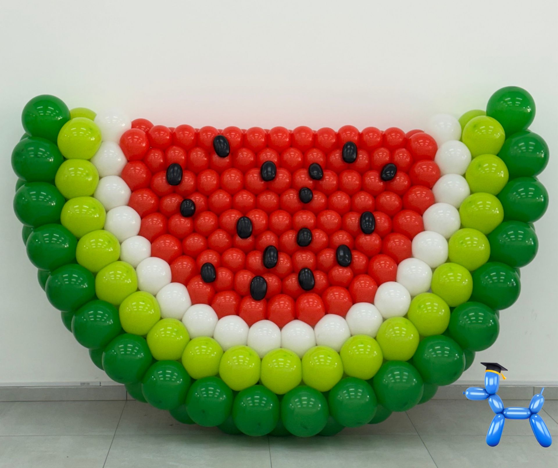 Watermelon balloon sculpture in red, white, lime green and dark green balloons with black balloons as the seeds