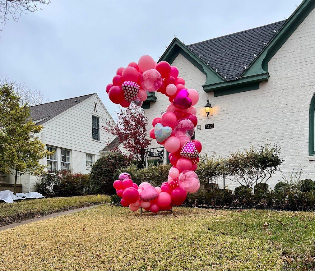 A large number 3 made of pink balloons in front of a white house.