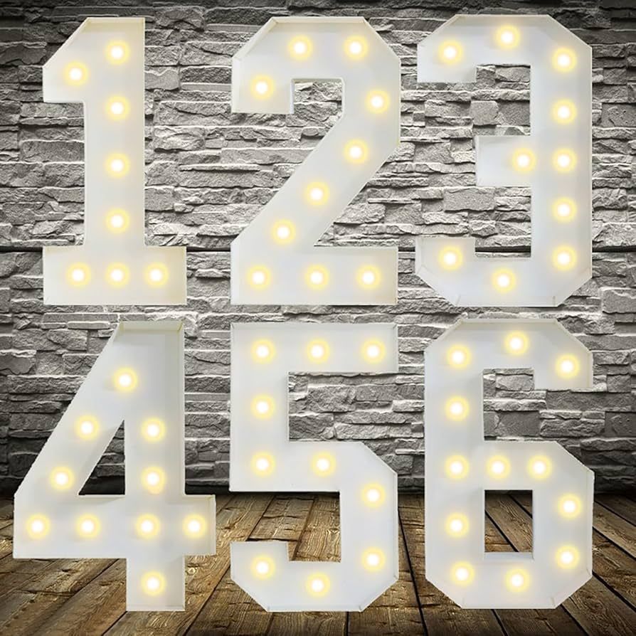 Large white LED marquee numbers 1 2 3 4 5 6 with bright warm yellow bulbs, perfect for birthday photo booth backdrop, milestone celebration decor, wedding table numbers, event signage, or nursery wall art on rustic brick wall background