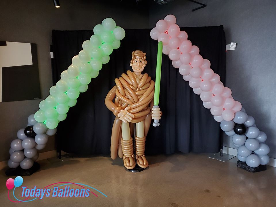 A statue of a man made out of balloons holding a light saber.