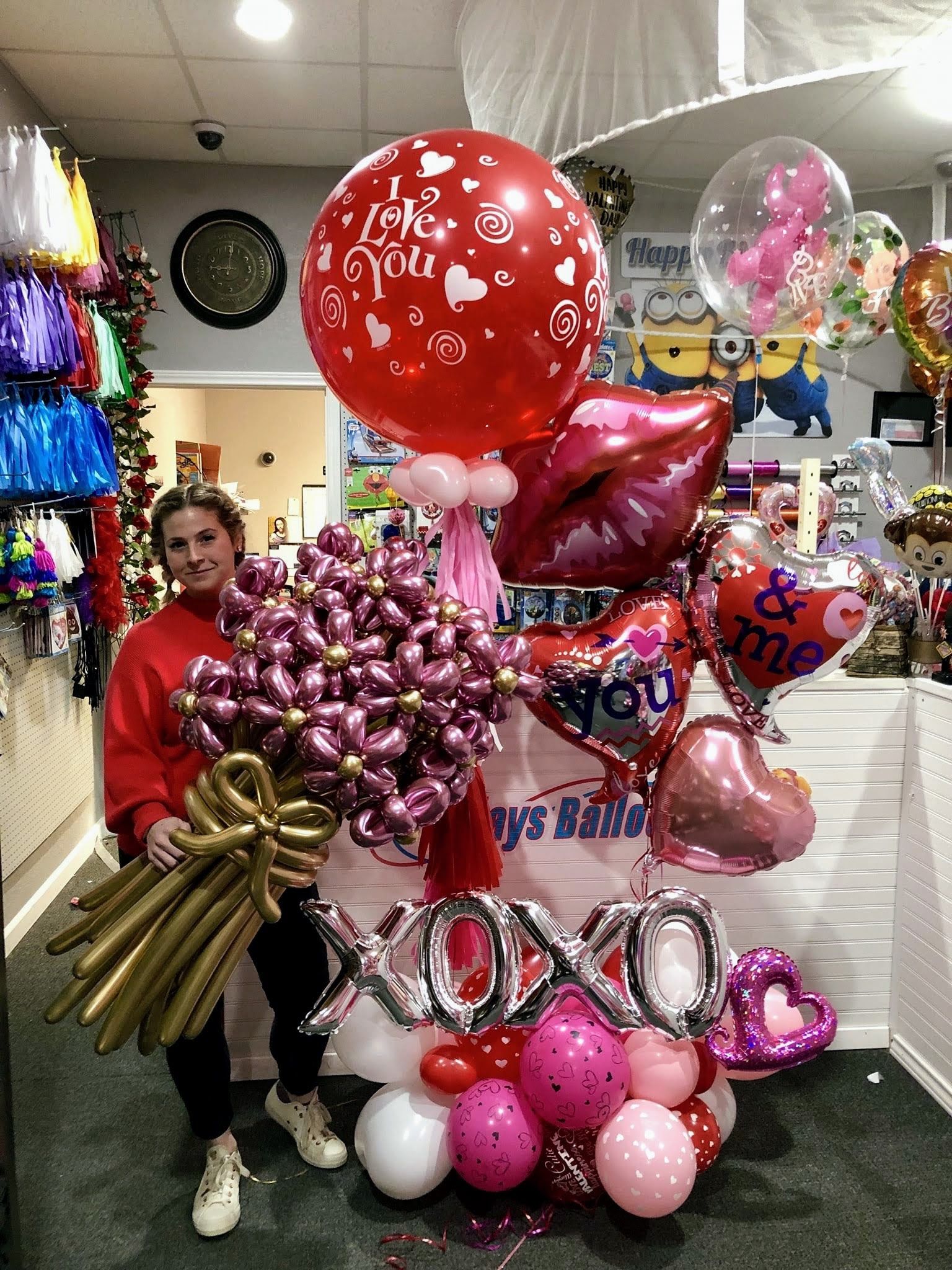 A woman is standing in front of a bunch of balloons.