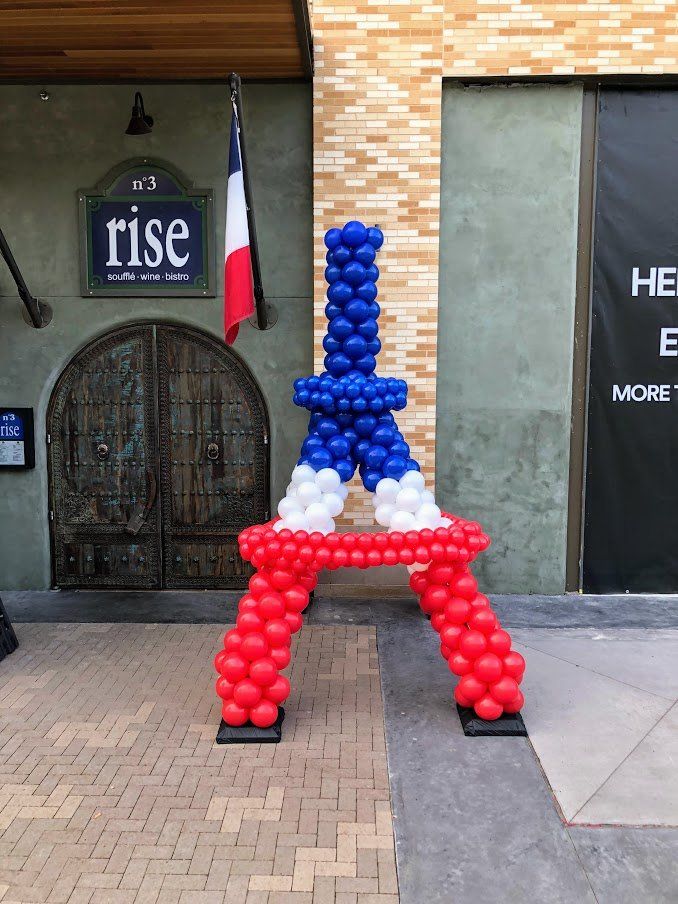 A large balloon shaped like the eiffel tower is in front of a building.