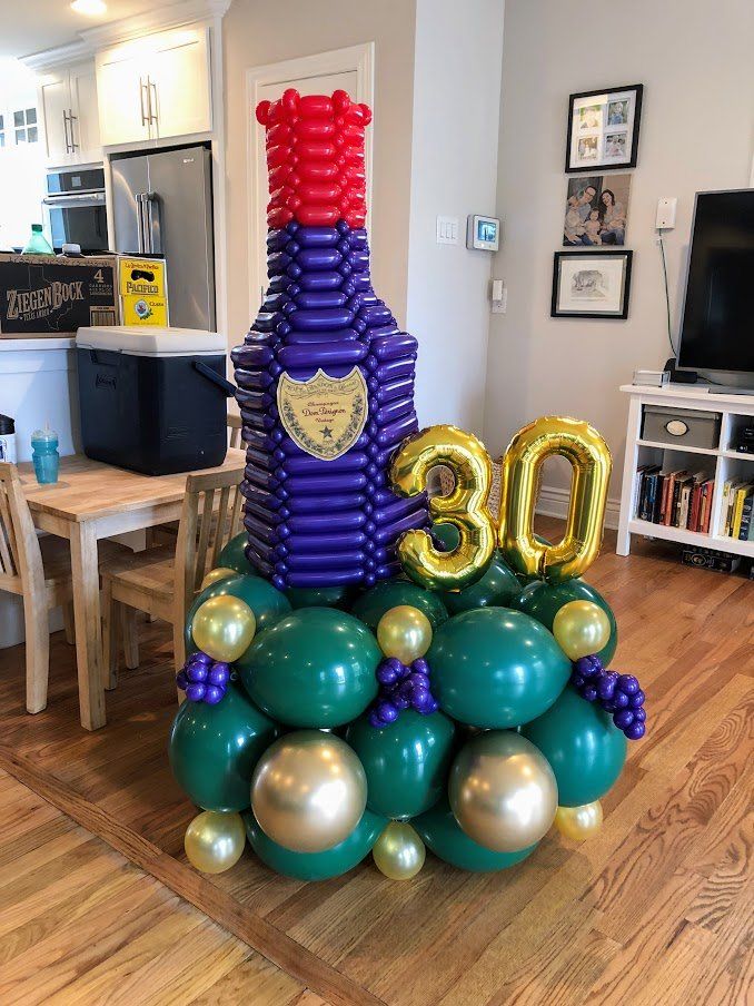 A bottle of wine made out of balloons in a living room.