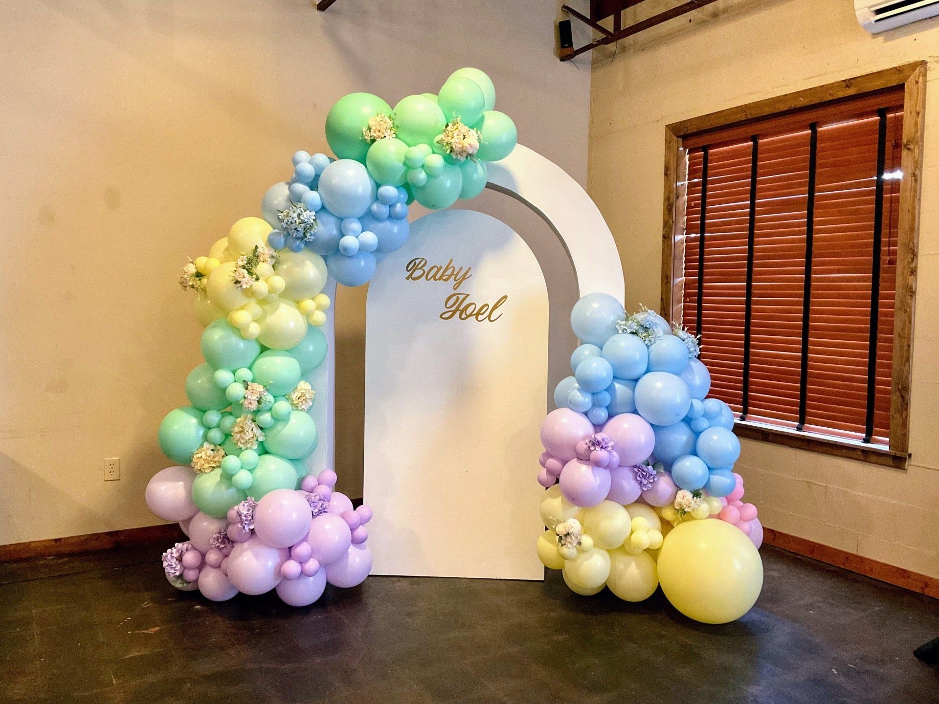 A room filled with balloons and a white arch.