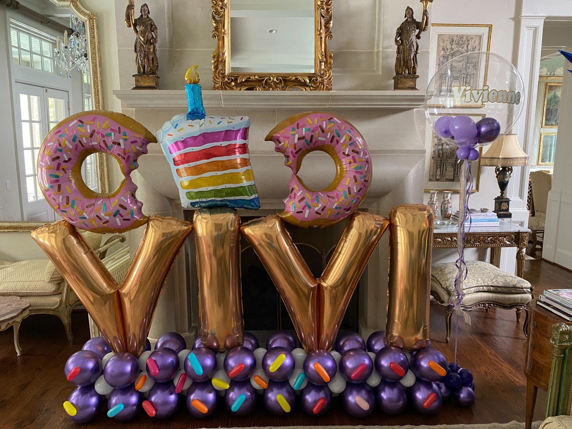 A living room decorated with donuts and balloons for a birthday party.