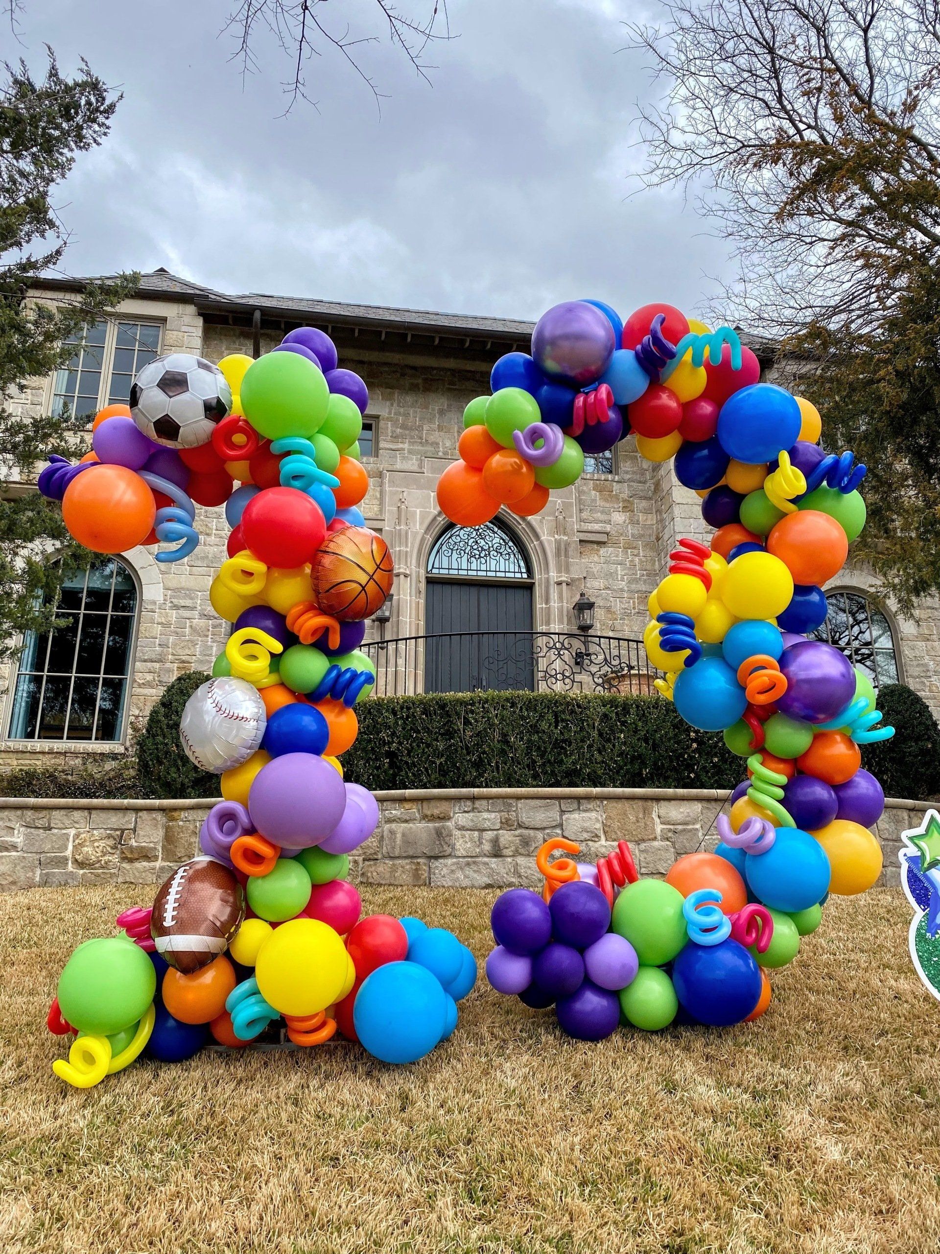 A bunch of colorful balloons are sitting in front of a house.